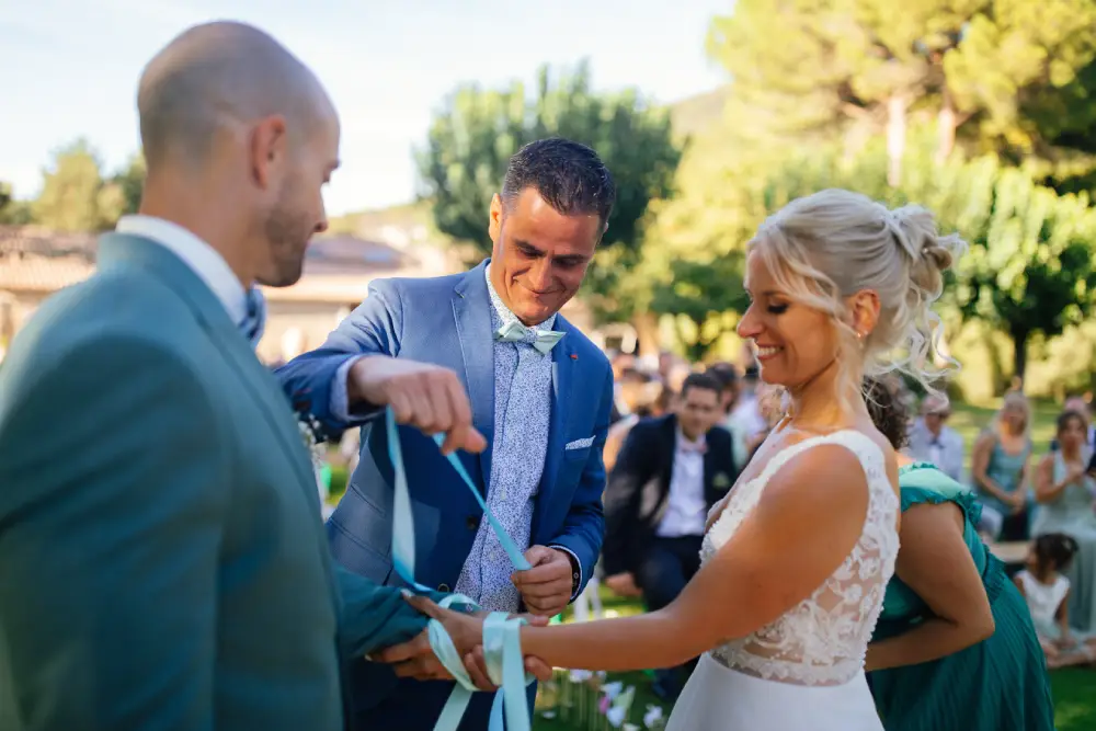 rituel des rubans pendant une cérémonie laïque. Un ami des mariés noue un ruban autour de leurs poignets