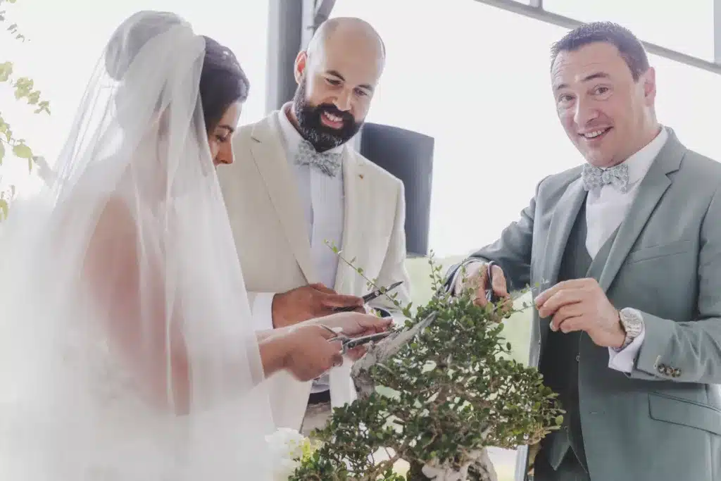 deux mariés et leur témoin en train de tailler un bonsaï